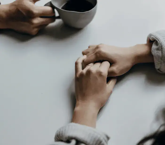 hands grasped together on a table